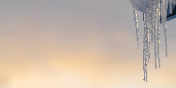 Искрящиеся сосульки на крыше на фоне неба
