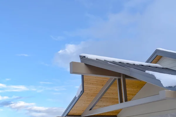 Neve coberto telhado contra o céu azul com nuvens — Fotografia de Stock