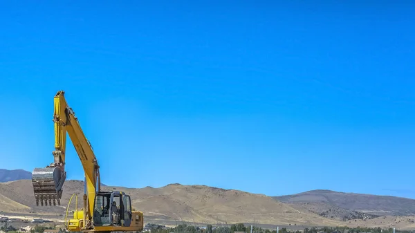 Construction vehicle against mountain and vast sky