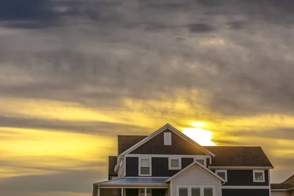 Casa contro il cielo con bagliore del tramonto e nuvole grigie — Foto Stock