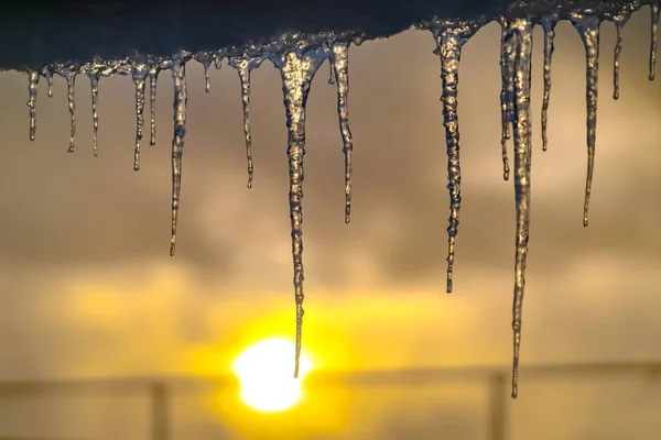 Carámbanos translúcidos colgando de un techo al atardecer — Foto de Stock