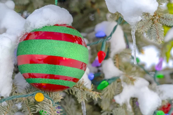 Bauble y luces en un árbol nevado con carámbanos — Foto de Stock