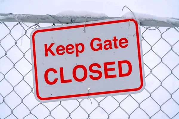 Fence with Keep Gate Closed sign against snow