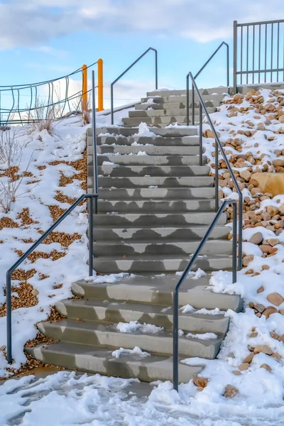 Stairs with melting snow against cloudy blue sky