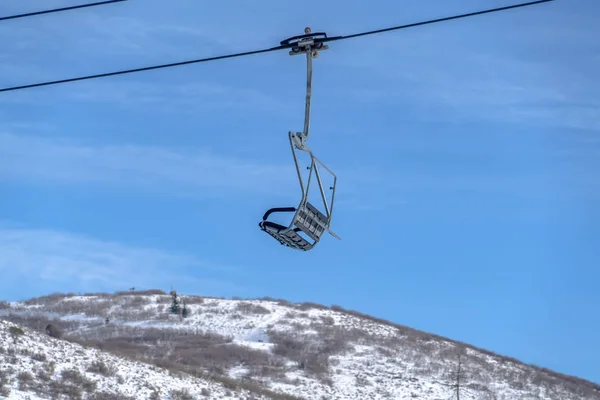Chair lift against snowy mountain and blue sky