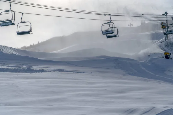 Chair lifts over mountain shrouded with snow