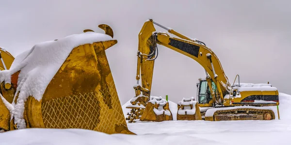 A bright yellow construction vehicles against snow