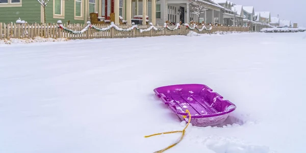 Puprle slitta sulla neve con le case sullo sfondo — Foto Stock