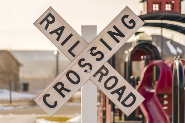 A Railroad Crossing sign with playground background