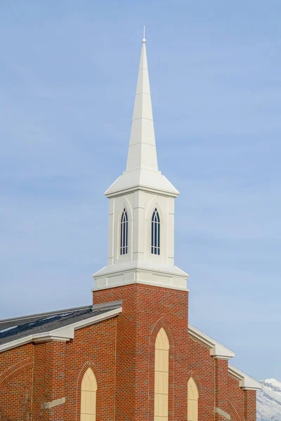 Церковь с красной кирпичной стеной и белым шпилем — стоковое фото