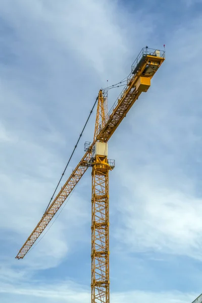 Construction tower crane against cloudy blue sky