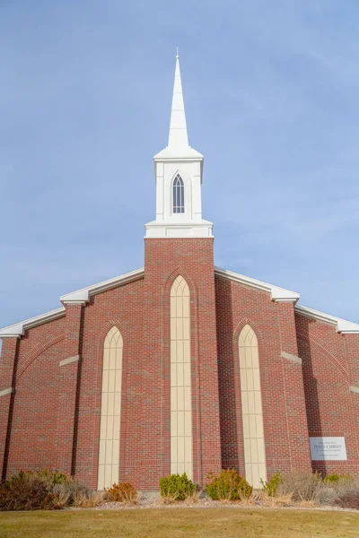 Фасад церкви с кирпичной стеной и белым шпилем — стоковое фото