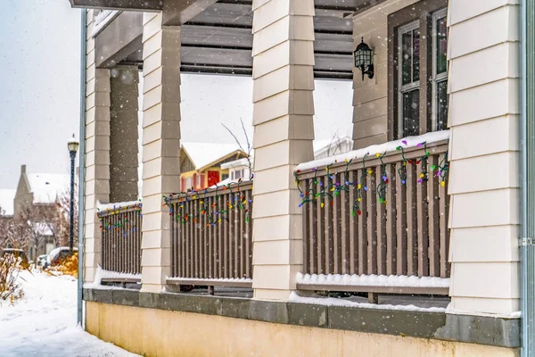Porch railing with colorful lights seen in winter