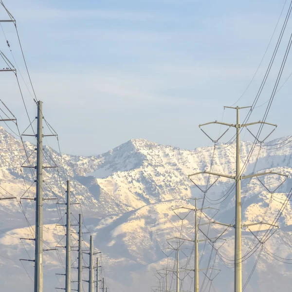 Power lines with snow capped mountain and sky view