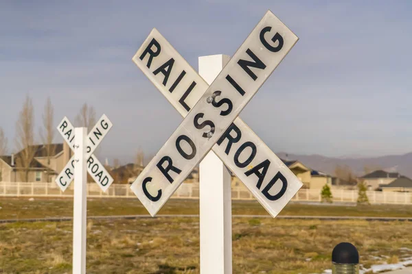 Railroad Crossing signs against homes and sky