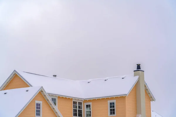 El techo cubierto de nieve de una casa contra el cielo en invierno — Foto de Stock
