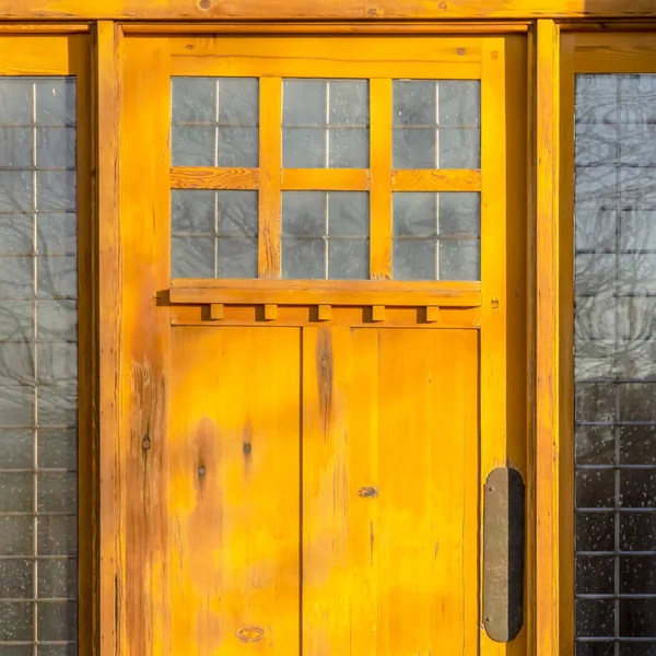 Sunlit wooden door with decorative glass panes — Stock Photo, Image