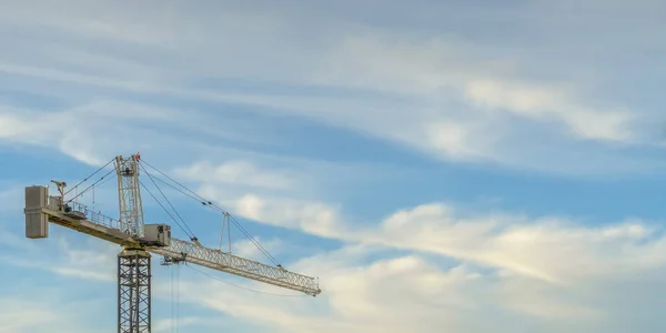 Tower crane against blue sky with puffy clouds