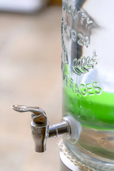 Close up of a glass beverage dispenser with faucet