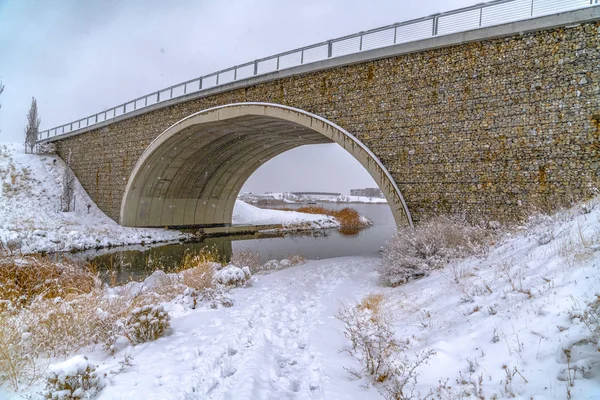 Huellas en sendero nevado pasando por debajo de un puente — Foto de Stock
