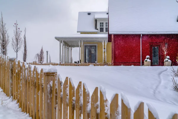 Wooden fence against snow and homes in winter