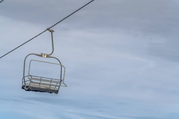 Elevador de cadeira vazio coberto com neve contra o céu — Fotografia de Stock