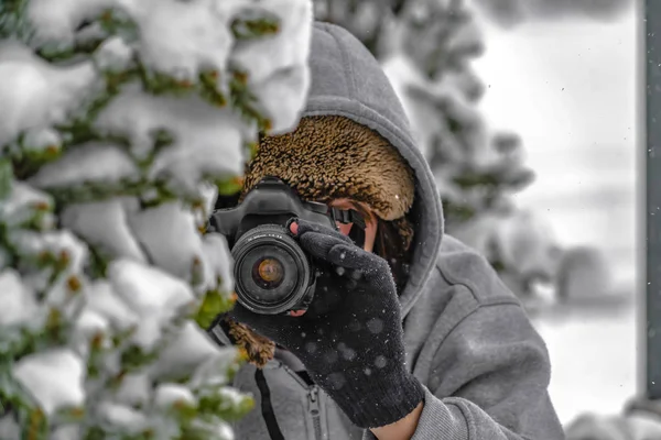 Photographer behind a snow covered tree in winter