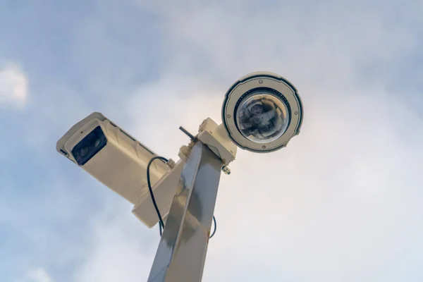 Close up of security cameras against cloudy sky