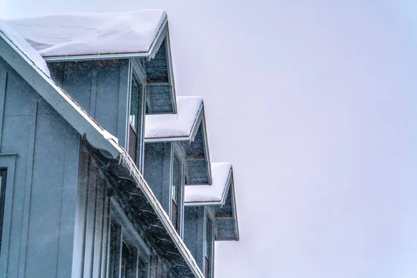 Hausaußenseite mit schneebedecktem Dach gegen den Himmel — Stockfoto