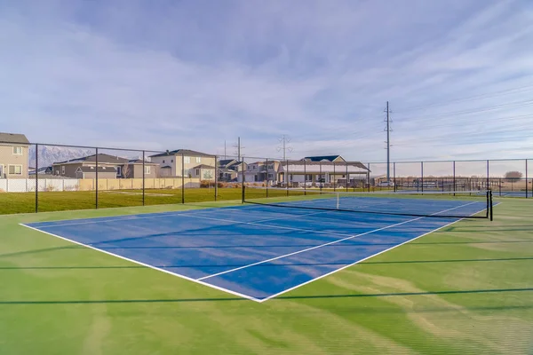 Pista de tenis contra hogares montaña y cielo — Foto de Stock