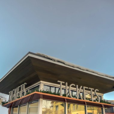 Mavi gökyüzüne karşı karlı çatılı bilet gişesi