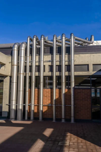 Building with metal pipes against vibrant blue sky — Stock Photo, Image