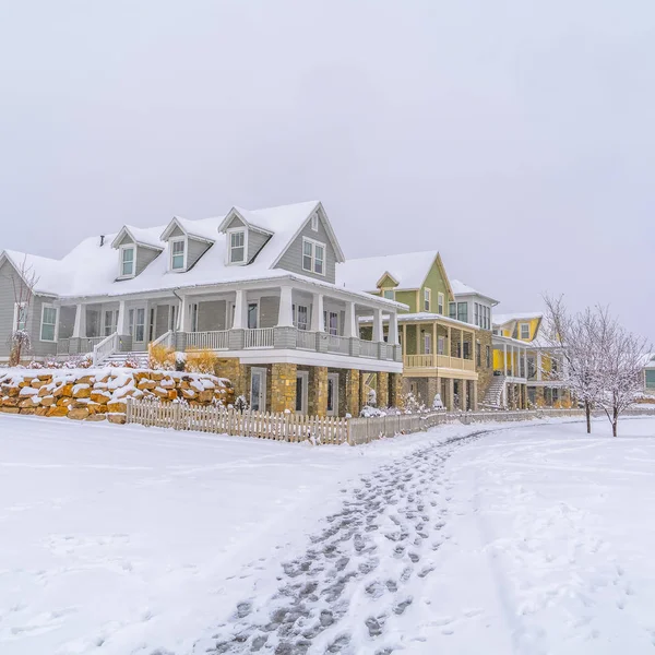 Casas nevadas y huellas en la nieve al amanecer — Foto de Stock