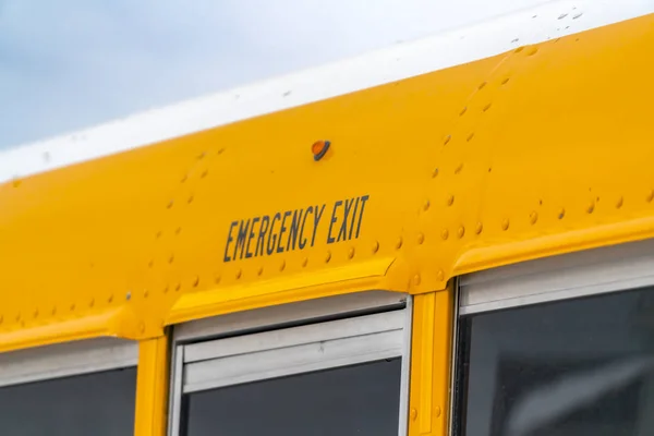 Close up of the exterior of a yellow school bus with an Emergency Exit sign
