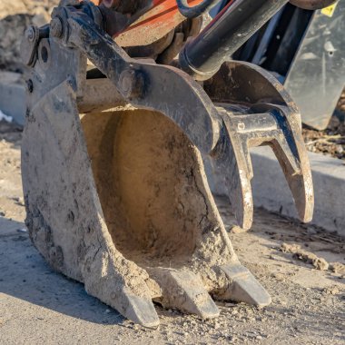 Clear Square Güneş ışığı ile aydınlatılmış bir yola karşı kırmızı bir ekskavatör metal kova yakın