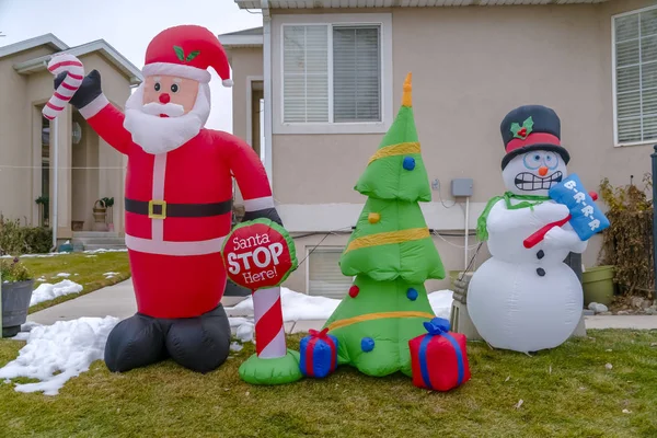 Decoraciones inflables de Navidad en un patio cubierto de hierba con nieve en invierno — Foto de Stock