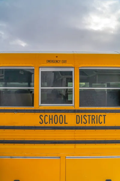 CLose up of the exterior of a yellow school bus against cloudy sky