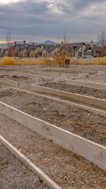 Arka planda bulutlu gökyüzüne karşı evleri ve dağ ile Dikey Yükseltilmiş bahçe yatakları