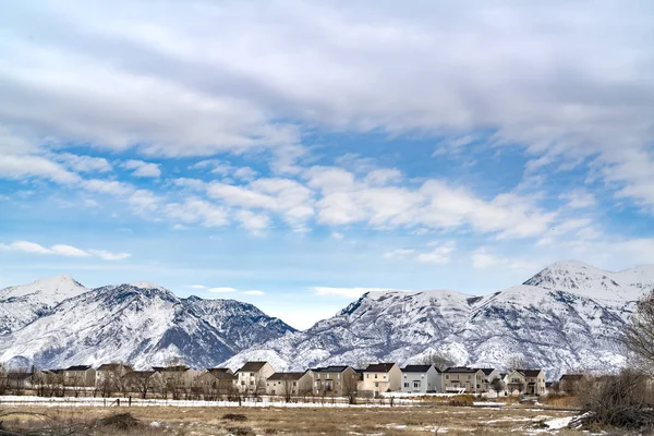 Beau ciel bleu avec des nuages gonflés sur les maisons et la montagne en hiver — Photo