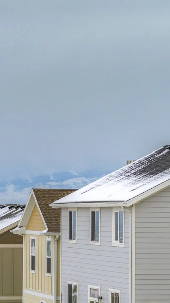 Vertikale gemütliche Häuser, die mit der schneebedeckten Landschaft während der Wintersaison kontrastiert — Stockfoto