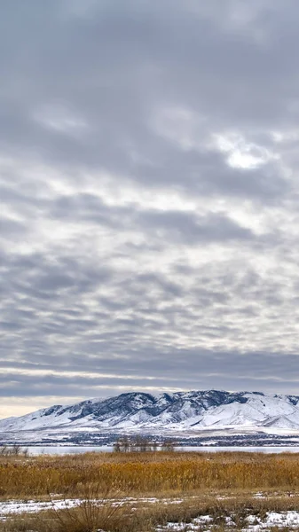 Vertical Cielo dramático lleno de nubes de algodón sobre un paisaje escénico en invierno —  Fotos de Stock