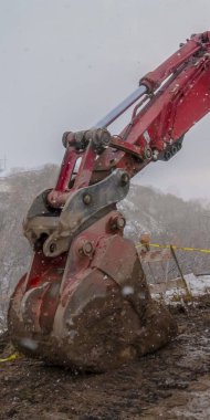 Kışın görülen barikatlar ve sarı bant ile çamurlu bir yolda Açık Dikey Ekskavatör
