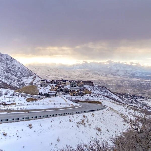 Чистая площадь, извивающаяся вдоль горы, покрытой снегом против облачного неба зимой — стоковое фото