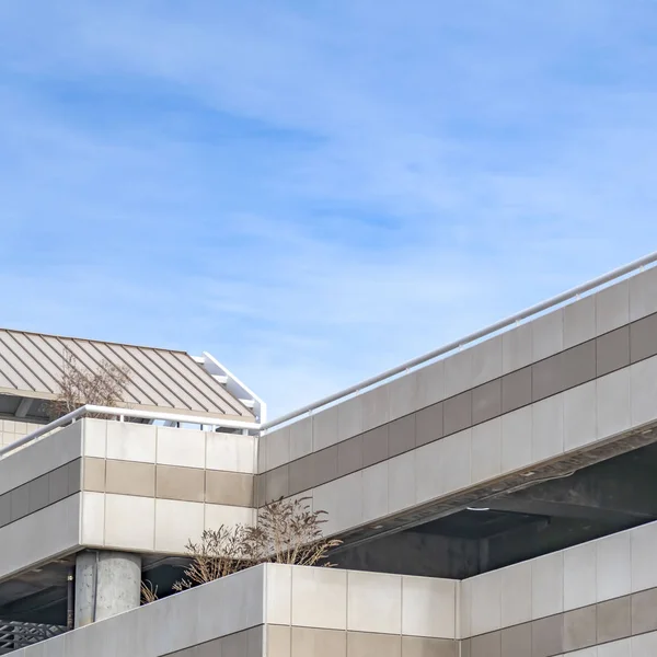 Freie quadratische Außenansicht des überdachten Parkplatzes eines Gebäudes mit Fahrzeugen und Pflanzen — Stockfoto