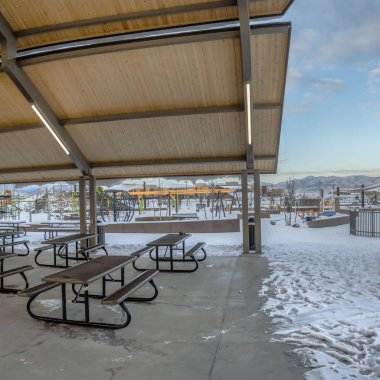 Kışın karla kaplı bir parkta Kare Kaplı piknik alanı ve oyun alanı