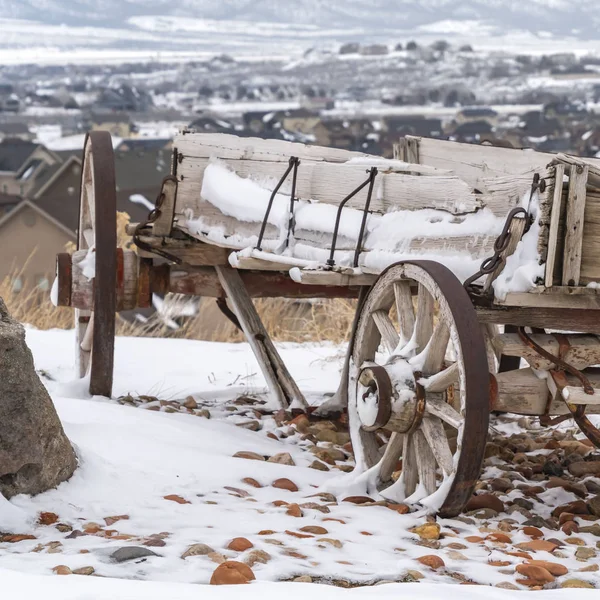 Vierkante oude houten wagon met kettingen en roestige wielen bestrooit met sneeuw in de winter — Stockfoto