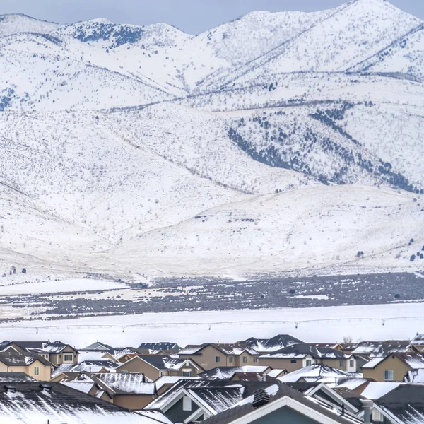 Cuadrados tejados nevados de casas con una vista impresionante de la montaña cubierta de nieve en invierno — Foto de Stock