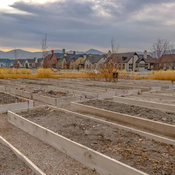 Clear Square Raised garden beds with homes and mountain against cloudy sky in the background