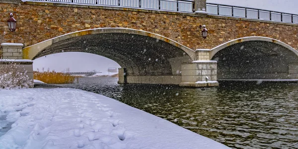 Sendero nevado a lo largo del lago y pasando por debajo de un puente — Foto de Stock