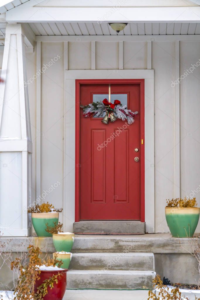Front door with glass panel and holiday decoration against a ribbed white wall